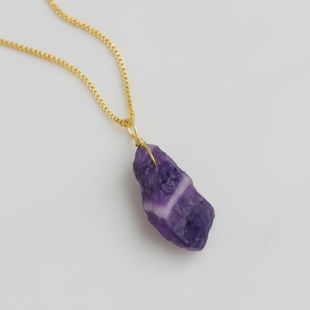 Purple crystal pendant on a gold chain against a white background